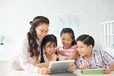 Öğrenciler ve öğretmen tablet bir şey izliyor