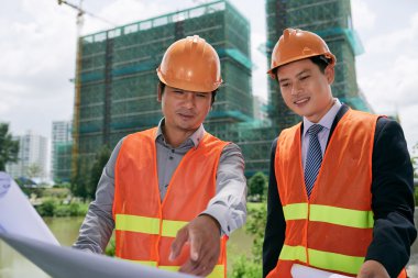 Blueprint inşaat sahasında inceleyerek mühendisleri