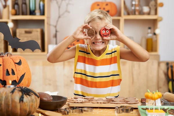 Menino cobrindo olhos com biscoitos de Halloween — Fotografia de Stock