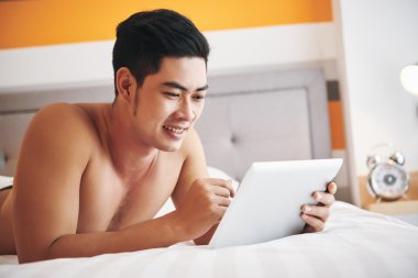 Dijital tablet ile yatakta yatan adam