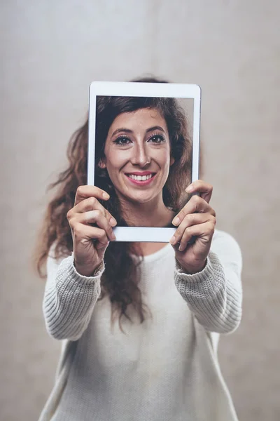Mulher segurando tablet digital na frente do rosto — Fotografia de Stock