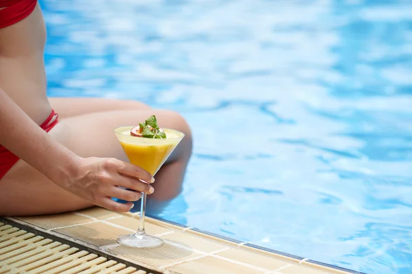 Vrouw zitten bij zwembad met cocktail — Stockfoto