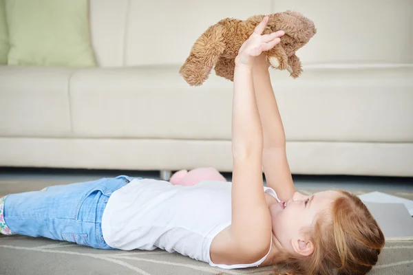 Smiling girl playing with bear — Stock Photo, Image