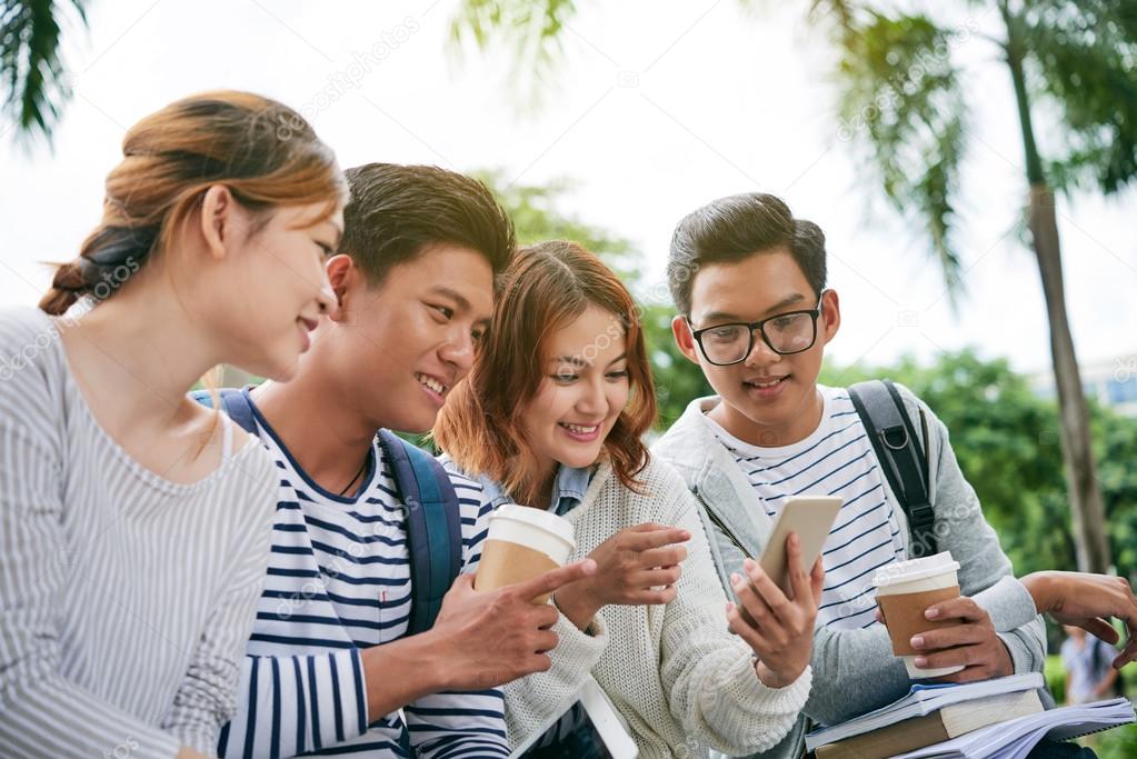 classmates looking at screen of smartphone