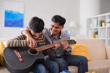 Father teaching son to play guitar clipart
