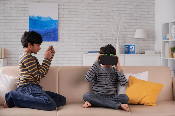 Boy photographing brother in VR goggles — Stock Photo, Image