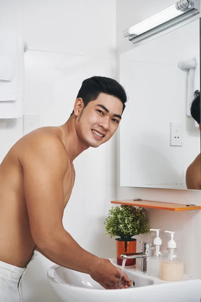 Man tvättar ansiktet i badrummet — Stockfoto
