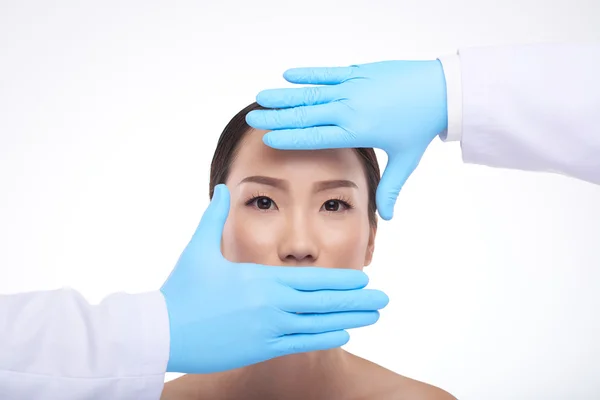 Manos del cosmetólogo frente a la cara de la mujer — Foto de Stock