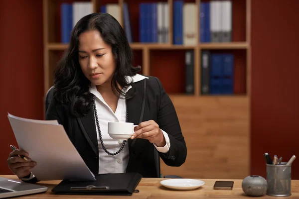 Señora bebiendo café y leyendo documento — Foto de Stock