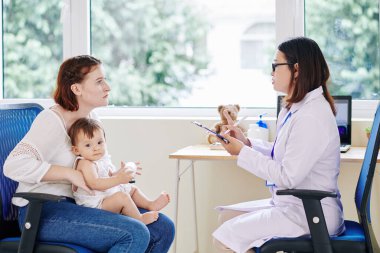 Çocuk doktoru, küçük hasta bir kızın annesine tavsiye veriyor.