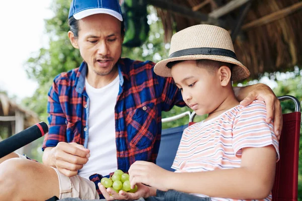Azjatycki Ojciec Syn Jedzący Winogrona Podczas Przerwy Łowieniu Razem — Zdjęcie stockowe