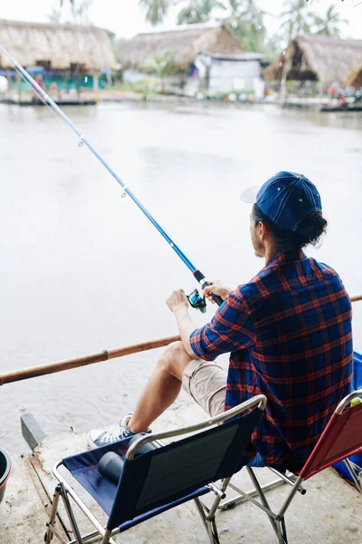 新しい回転と湖で折りたたみ椅子や釣りに座って成熟した男 背中からの眺め — ストック写真