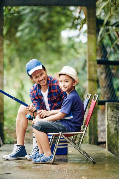 かわいい笑顔の男の子に座って折りたたみ椅子と釣りで回転と彼のお父さん — ストック写真