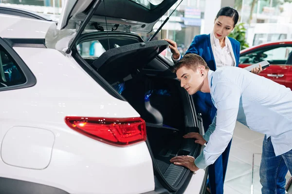 Bonito Jovem Olhando Dentro Carro Tronco Concessionária — Fotografia de Stock