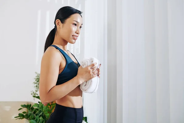 Smiling Asian Sportswoman Towel Hands Looking Window Her Room — Stock Photo, Image