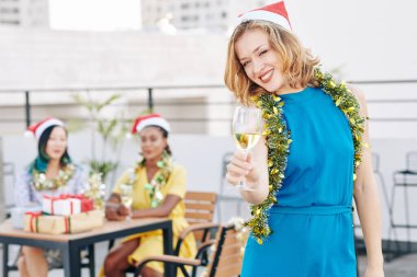 Noel 'i arkadaşlarıyla kutlarken bir kadeh şampanyayla kadeh kaldıran güzel sarışın genç kadının portresi.