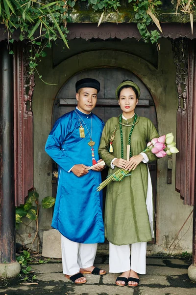 Serious Young Vietnamese Couple Traditional Dai Dresses Holding Lotus Flowers — Stock Photo, Image