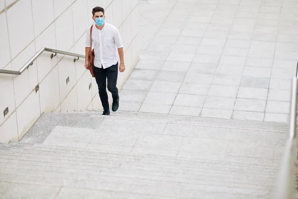 一个戴着医疗面具的严肃的年轻人走在城里的楼梯上 — 图库照片