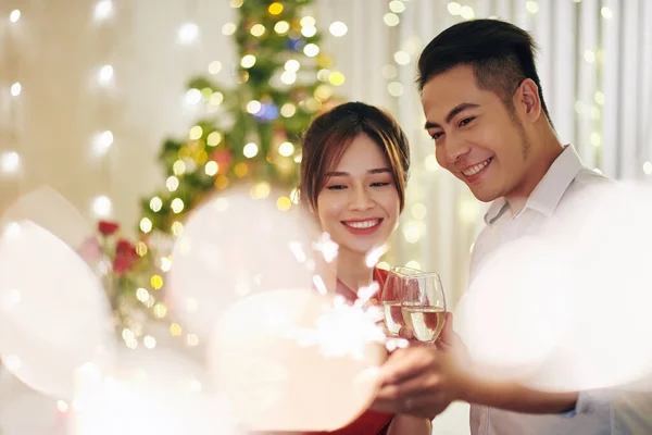 自宅でクリスマスを祝うときに美しい幸せな笑顔ベトナムのカップルはシャンパンを飲む — ストック写真