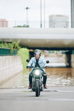 Şehirde motosiklet süren ciddi Vietnamlı genç bir adam.