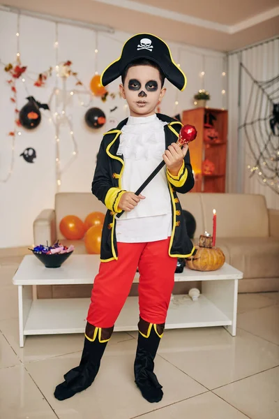 Boy in pirate Halloween costume holding scepter when standing in room decorated for Halloween party