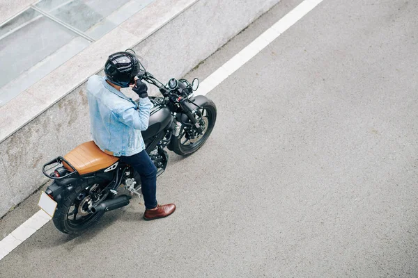 デニムジャケットの男はヘルメットを調整し オートバイに乗る準備をする — ストック写真