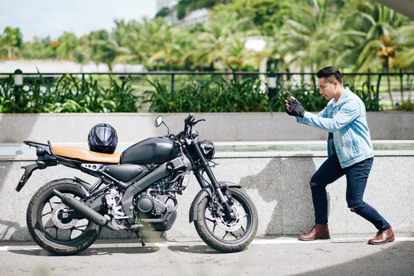 Yakışıklı Asyalı Genç Adam Akıllı Telefonuyla Motosikletinin Fotoğrafını Çekiyor — Stok fotoğraf