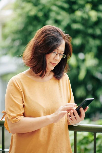 Mature Wanita Vietnam Dalam Gelas Memeriksa Pesan Teks Smartphone Ketika — Stok Foto