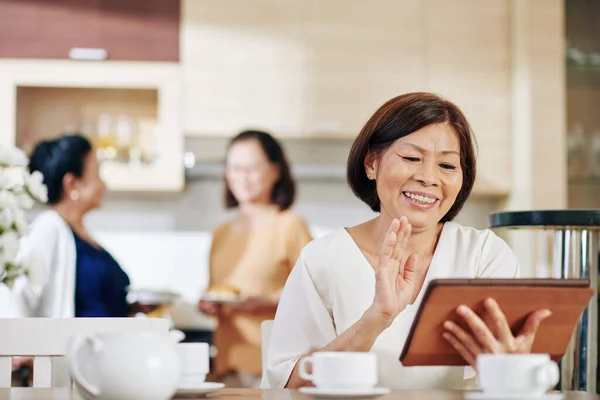 Χαμογελώντας Ηλικιωμένη Γυναίκα Ψηφιακή Ταμπλέτα Κάθεται Στο Τραπέζι Της Κουζίνας — Φωτογραφία Αρχείου