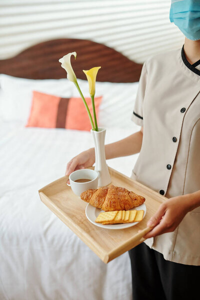 Cropped image of maid bringing fresh coffee, croissant and cookies in hotel room of guest