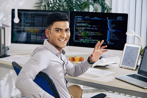 Glücklich Aufgeregter Indischer Softwareentwickler Sitzt Schreibtisch Dreht Sich Und Winkt — Stockfoto