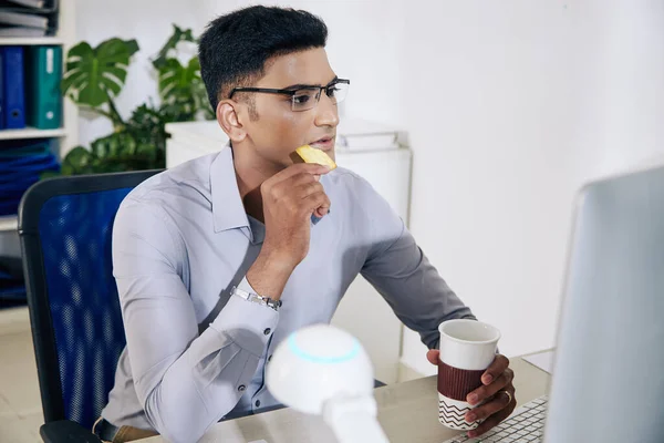 Pensive Jovem Desenvolvedor Software Indiano Copos Beber Café Comer Biscoito — Fotografia de Stock