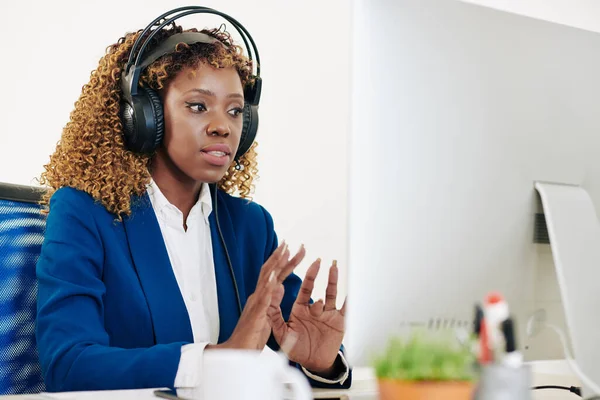 漂亮的年轻黑人女性技术支持专栏作家在耳机中接听客户电话 — 图库照片
