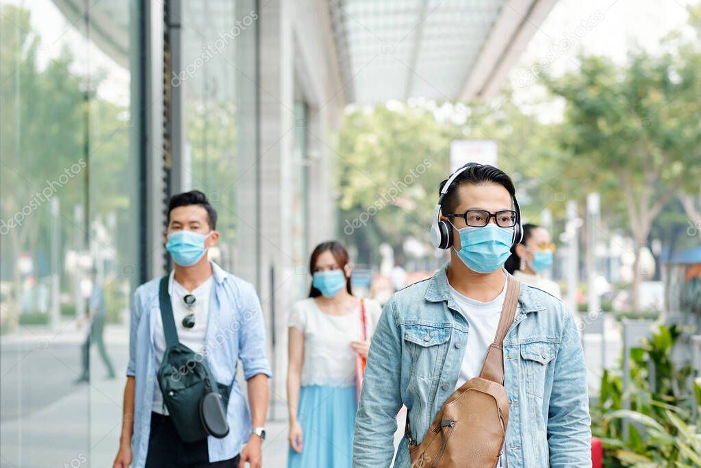 Young people in medical masks walking down the city street