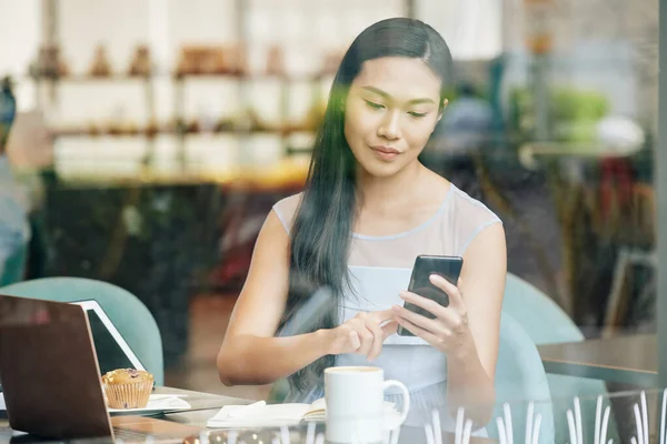 Csinos Fiatal Kínai Dolgozik Asztalnál Kávézóban Ellenőrzi Szöveges Üzenetek Smartphone — Stock Fotó