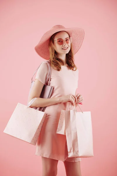 スタジオポートレートの笑顔かわいいです若いです女性とともにショッピングバッグポーズピンクの背景 — ストック写真