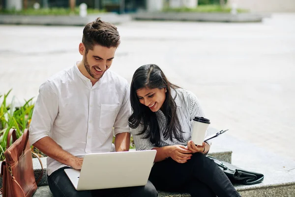 Smiling young business people discussing project presentation on laptop screen