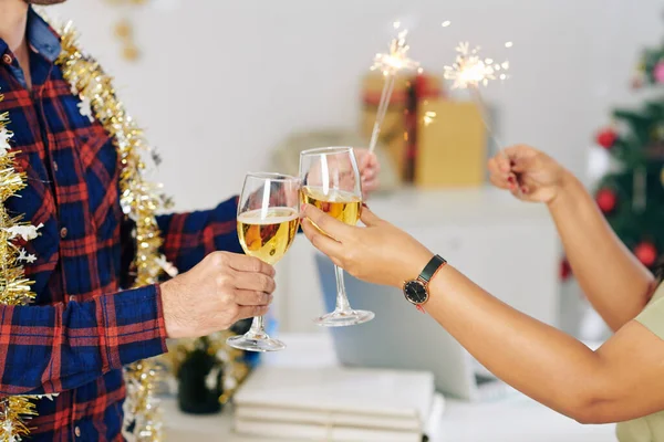 オフィスで新年を祝うときにベンガルのライトを燃焼し シャンパングラスで乾杯する同僚の手 — ストック写真