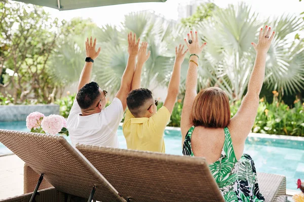 お父さん お母さん お子さんがプールでシャイなラウンジに座って 素晴らしい休暇を祝うときに手を上げて — ストック写真