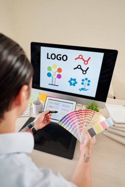 Ellerinde renk paleti olan grafik tasarımcısı şirket logosu oluşturuyor