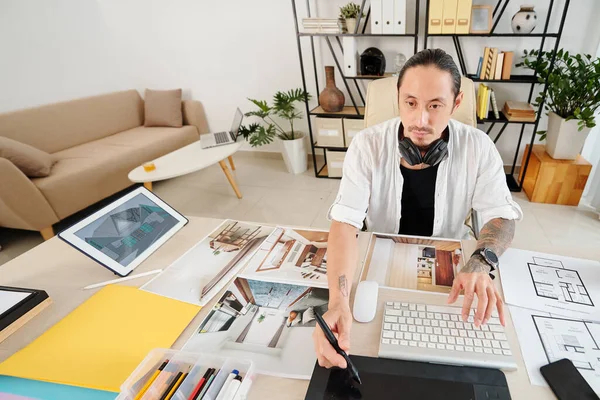 クライアントのための大きな家のインテリアデザインに取り組むプロのデザイナー 彼は計画や写真とテーブルに座っています — ストック写真