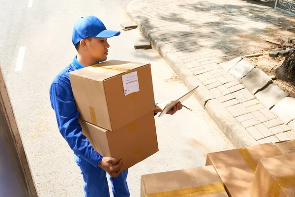 亚洲的年轻送货服务人员在卸货时查询数码平板电脑的数据 — 图库照片