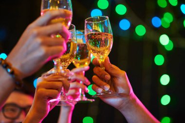 Gece kulübünde yeni yılı kutlarken kadehlerini şampanya kadehleriyle kaldıran gençlerin görüntüsü.