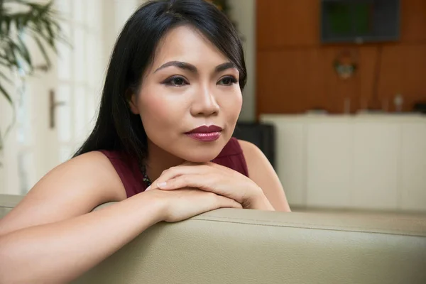 忧心忡忡的年轻亚洲女人靠在沙发上沉思自己的生活的画像 — 图库照片