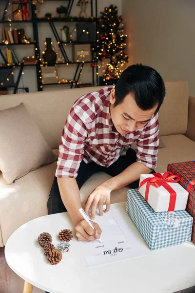 Sourire Jeune Homme Asiatique Remplissant Liste Des Cadeaux Enveloppant Cadeaux — Photo