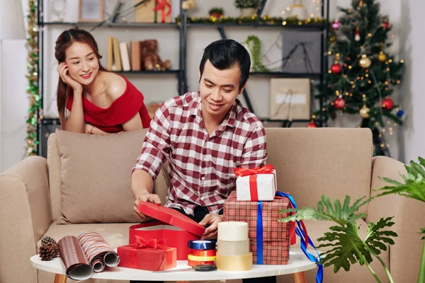 Hübsch Lächelnde Junge Asiatin Schaut Ehemann Beim Einpacken Von Weihnachtsgeschenken — Stockfoto