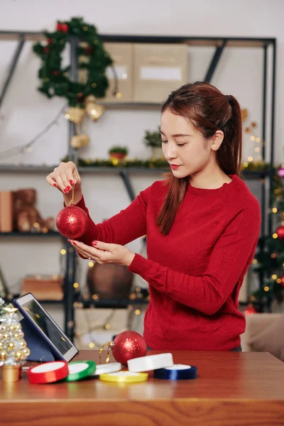 Pretty Young Asian Woman Looking Sparkling Red Bauble Her Hands — ストック写真