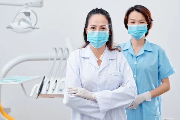 Опытный Азиатский Стоматолог Медсестра Медицинских Масках Стоящих Стоматологическом Кабинете Смотрящих — стоковое фото
