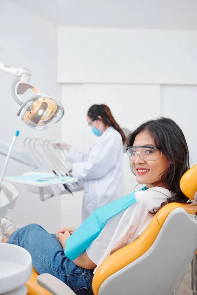 Dişçi Koltuğunda Oturan Kameraya Gülümseyen Dişçi Arka Planda Işi Seçen — Stok fotoğraf