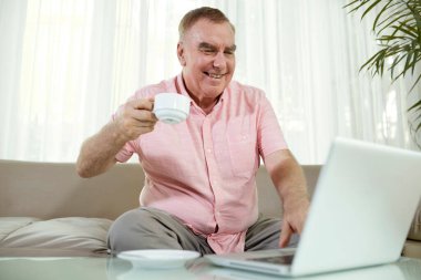 Neşeli yaşlı bir adamın portresi bir fincan kahve ve video içen arkadaş ya da aile ferdi